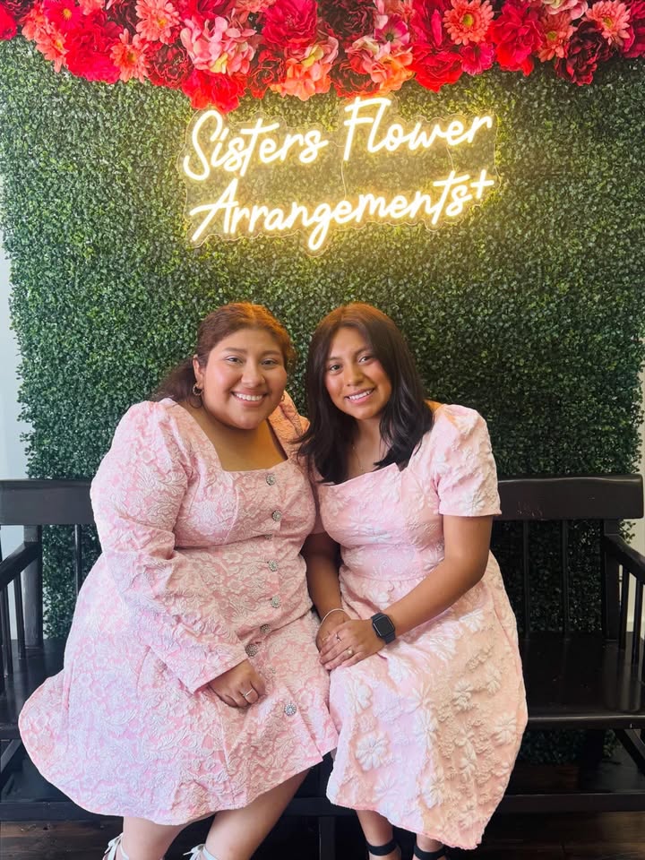 Yasmin and Gregoria Rivera Cansinos, founders of Sisters Flower Arrangements, under their shop's neon sign